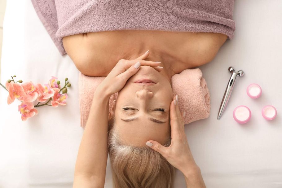 Eine Frau genießt eine entspannende Gesichtsmassage in einem Kosmetikstudio, umgeben von Babor-Produkten und Orchideen.