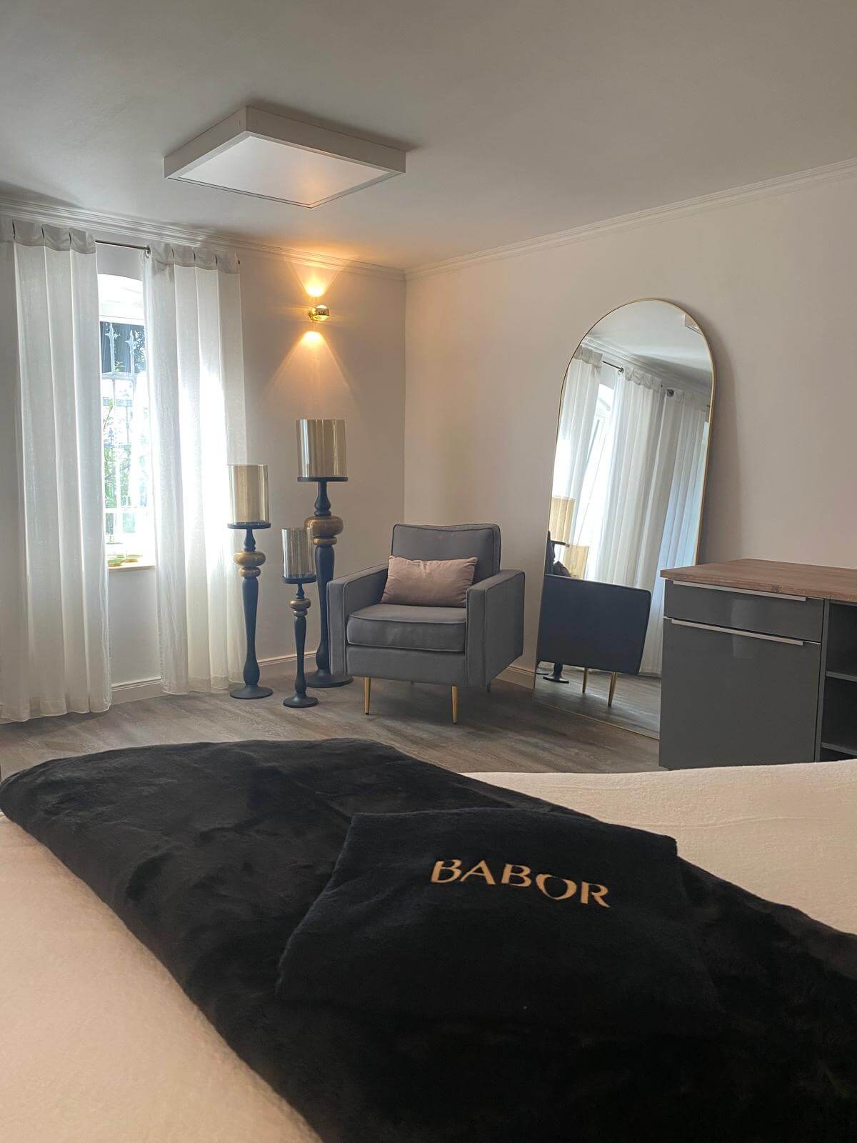 Ein elegantes Kosmetikstudio mit einem gemütlichen Sessel und einer Decke mit Babor-Logo lädt zur Entspannung ein.