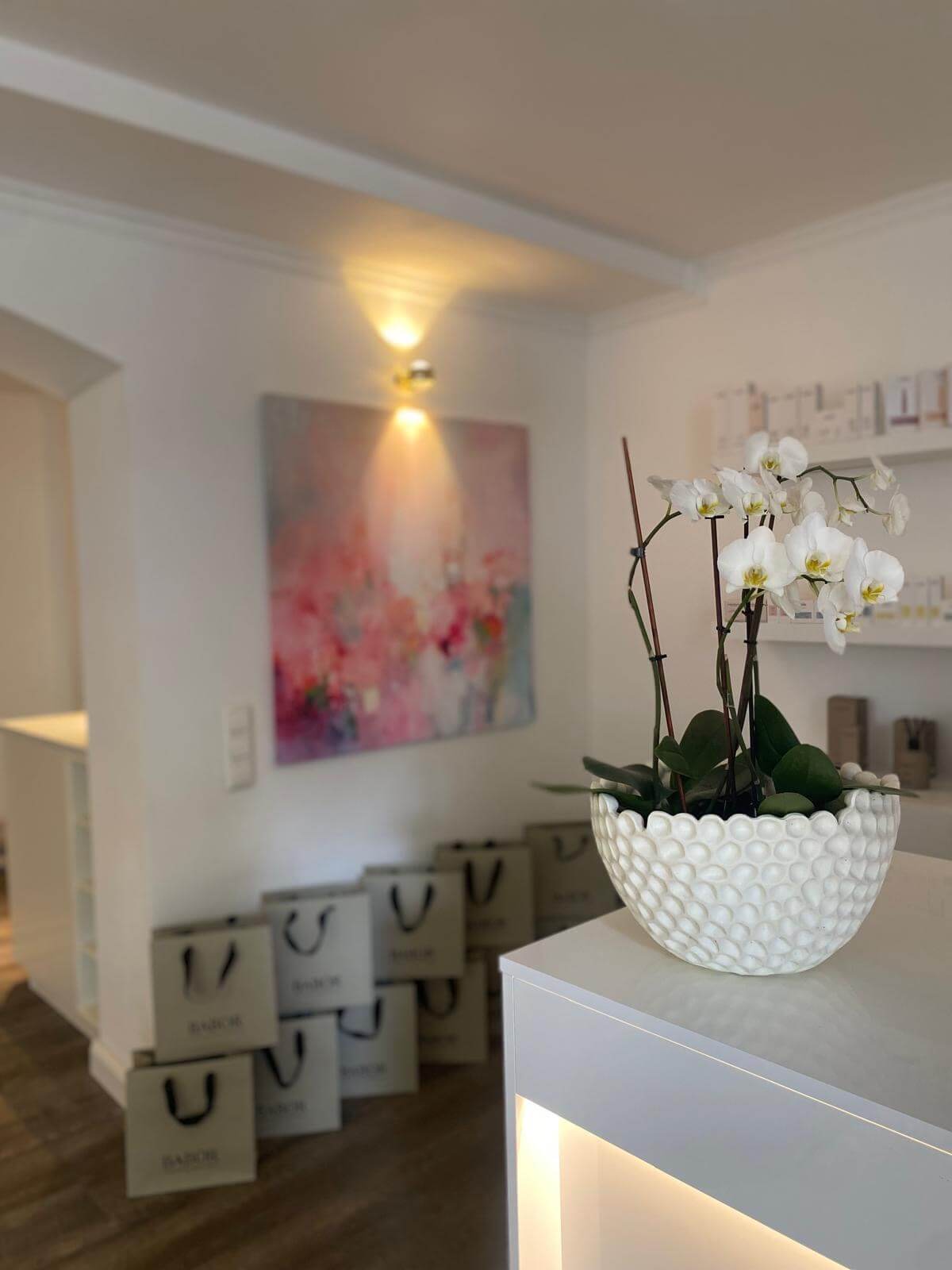 Eine elegante Orchidee ziert den Tresen eines modernen Kosmetikstudios, umgeben von Babor-Einkaufstaschen.